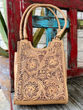 ADBGZ767A — Women's pale natural tan vegetable-tanned cowhide structured tote with deep full-coverage floral and acanthus leaf scroll hand-tooling with dark brown/mahogany antiqued contrast, two braided/plaited round leather top handles, and whipstitch lace trim along all outer edges — Blair's Western Wear Marble Falls TX