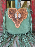 ADBGA431D — Angled view of women's sage green suede fringe crossbody showing sculpted hand-tooled floral feather flap with two white painted feathers and cream whipstitch trim, with the tan hand-tooled feather-scroll crossbody strap and antique brass swivel hardware displayed in front — Blair's Western Wear Marble Falls TX