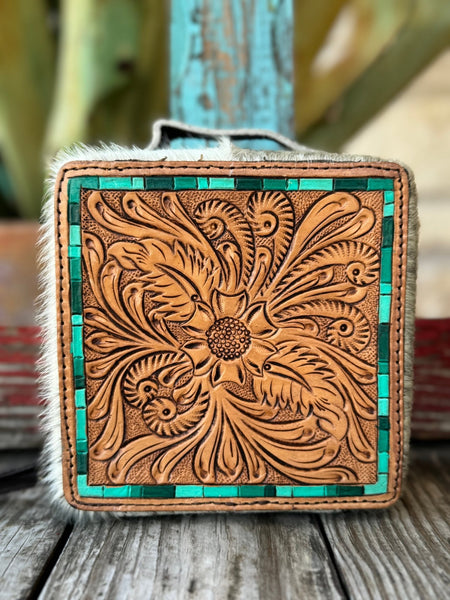 This jaw-dropping jewelry case features a hand-tooled sunflower and feather scroll leather lid in natural tan with a stunning turquoise tile inlay border, wrapped in white and cream natural hair-on cowhide — it's western artisan style that belongs on your dresser — Blair's Western Wear Marble Falls TX