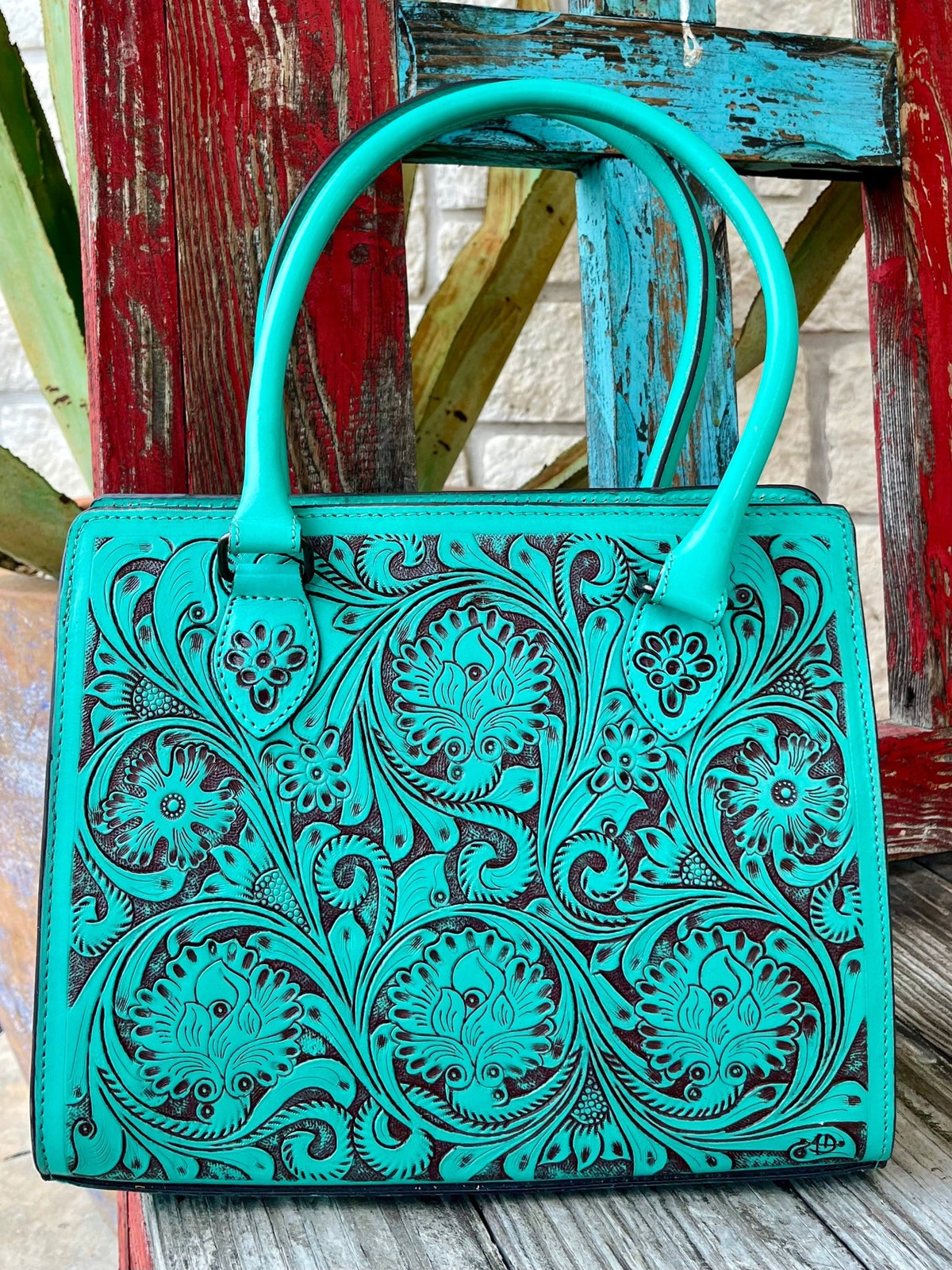 ADBGZ732B — Women's structured turquoise and dark brown full-coverage floral and scroll hand-tooled leather satchel with vibrant turquoise dye on raised carved surfaces over dark chocolate/espresso brown leather base, multiple large circular floral medallions with sweeping acanthus scroll and leaf carving across entire front panel, smooth matching turquoise leather top handles, top-center zip closure with leather pull tab, dark chocolate leather base trim, and American Darling AD brand stamp on lower right 