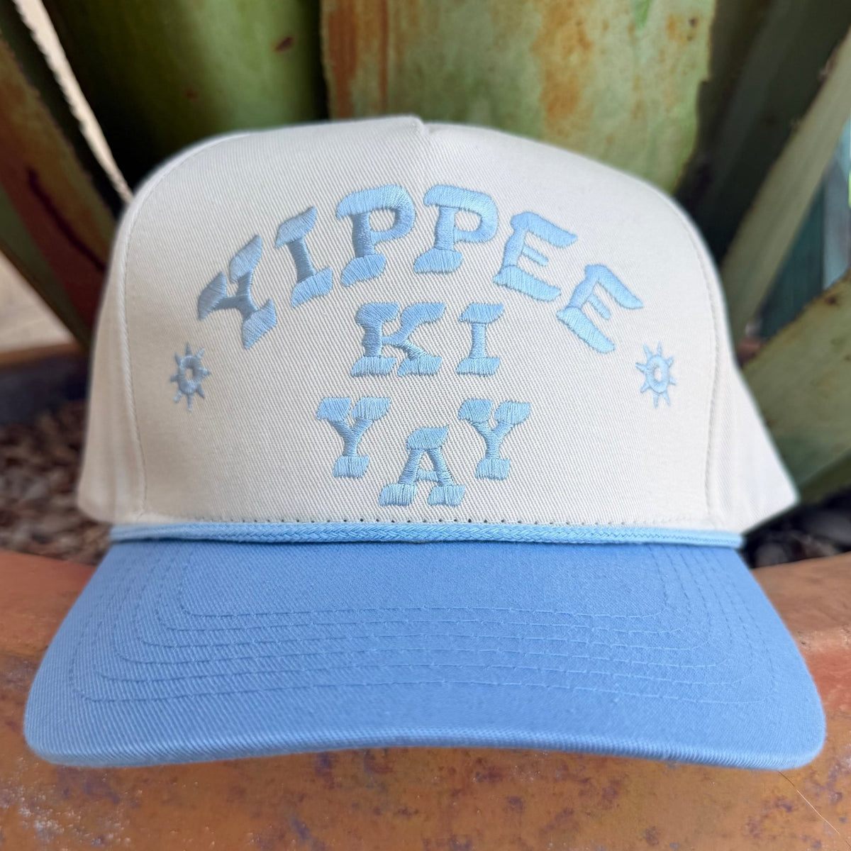 An off- white and light blue cap with 'YIPPEE KI YAY' embroidered on the front, 