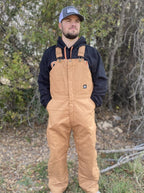 Men's tan insulated duck bib overalls with adjustable straps, reinforced knees, and full-length leg zippers — Blair's Western Wear Marble Falls TX